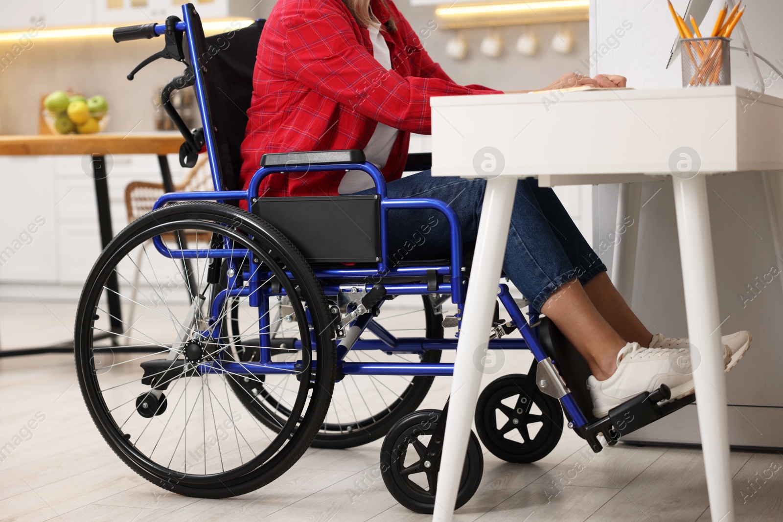 Photo of Woman in wheelchair at table indoors, closeup