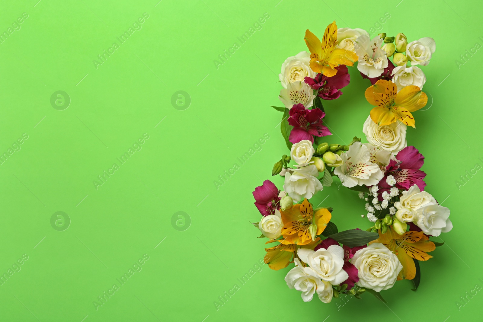 Photo of Number 8 made of beautiful flowers on green background, flat lay with space for text. International Women's day