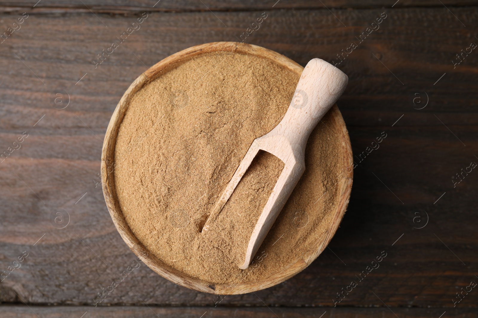 Photo of Dietary fiber. Psyllium husk powder in bowl and scoop on wooden table, top view