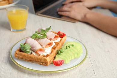 Woman working with laptop at wooden table during breakfast