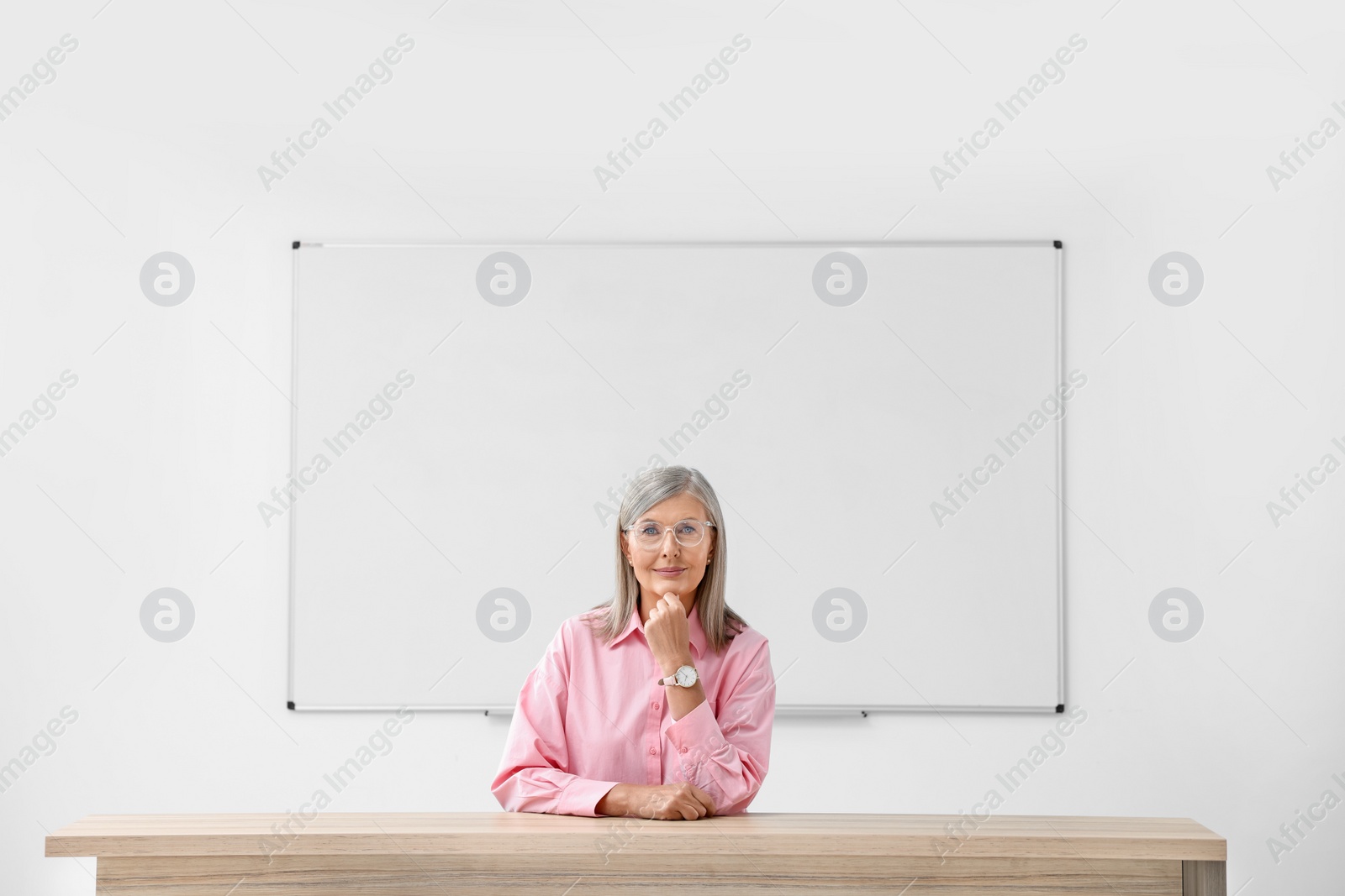 Photo of Portrait of professor sitting at desk in classroom