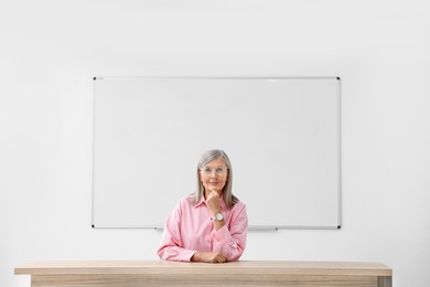 Portrait of professor sitting at desk in classroom