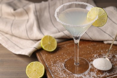 Photo of Martini glass of refreshing cocktail with lime and sugar on wooden table, closeup