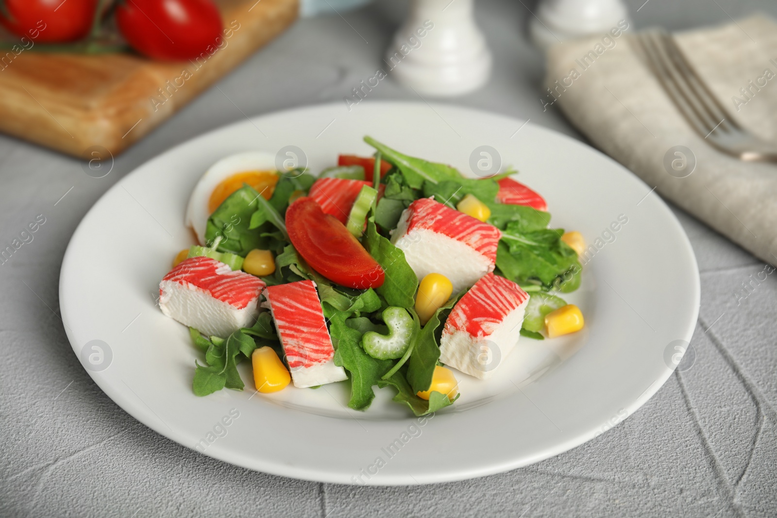 Photo of Delicious crab stick salad served on grey table