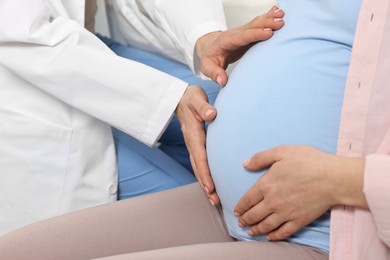 Photo of Pregnancy checkup. Doctor examining patient's tummy in clinic, closeup