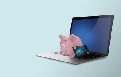 Image of Piggy bank with credit card and laptop on light blue background. Online banking