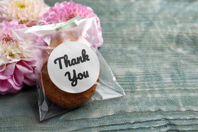 Photo of Bag of cookies with phrase Thank you and flowers on grey wooden table, space for text