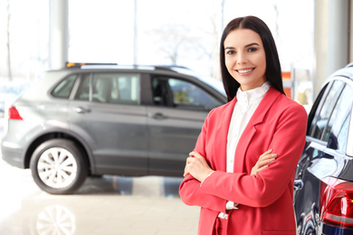 Happy young saleswoman in modern car salon