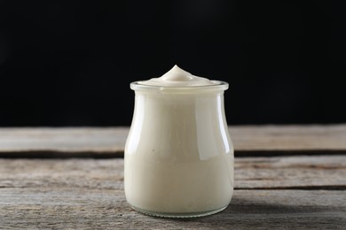 Photo of Fresh mayonnaise sauce in glass jar on wooden table