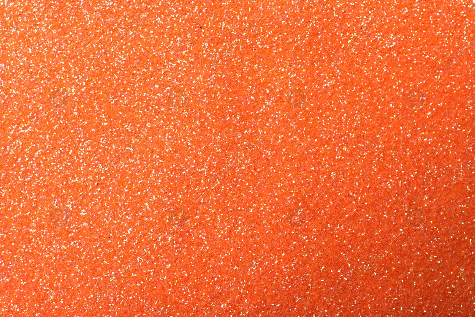 Photo of Beautiful shiny orange glitter as background, closeup