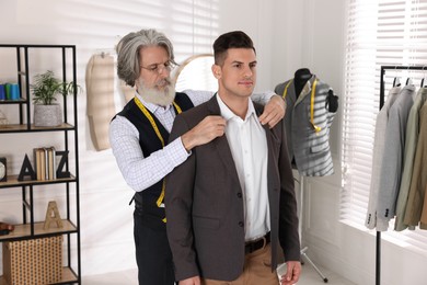 Professional tailor working with client in atelier