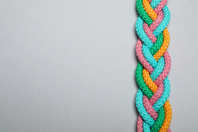 Top view of braided colorful ropes on light grey background, space for text. Unity concept
