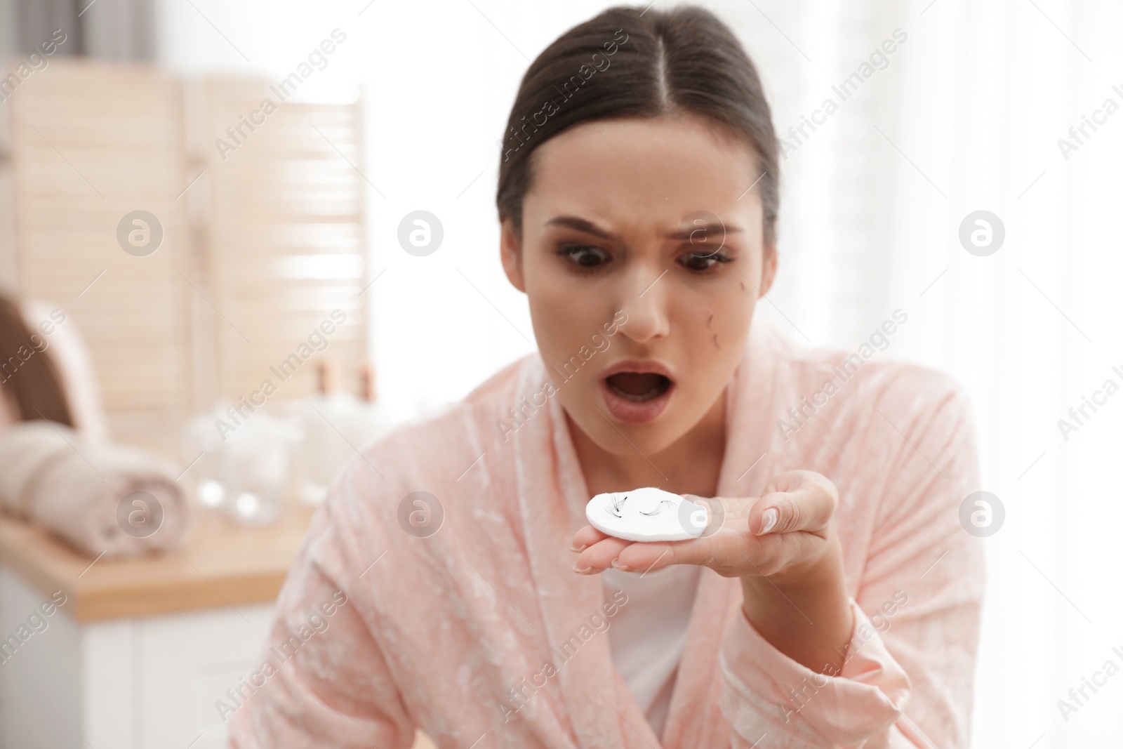 Photo of Beautiful woman holding cotton pad with fallen eyelashes indoors