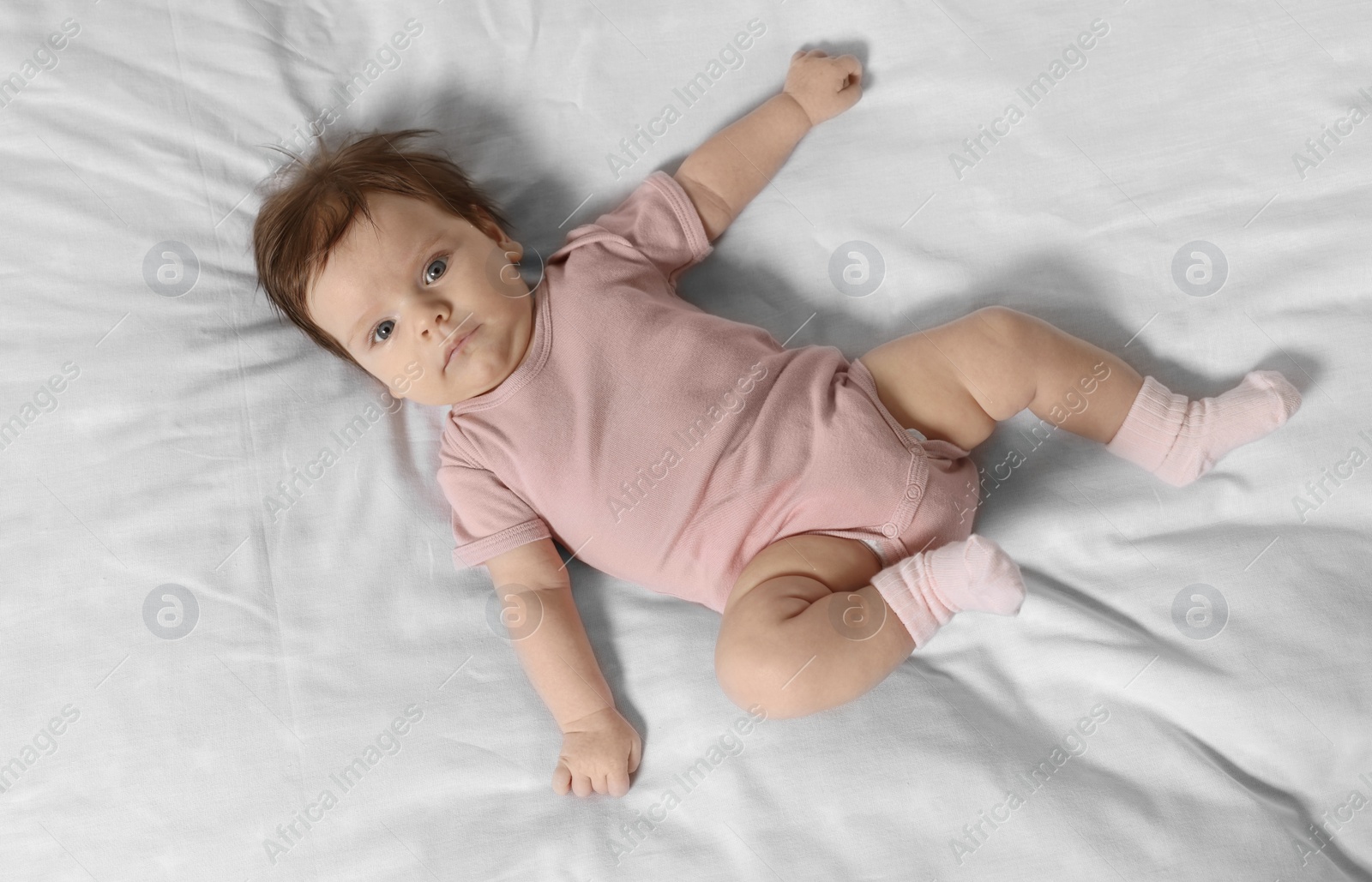 Photo of Cute little baby on cosy bed, top view