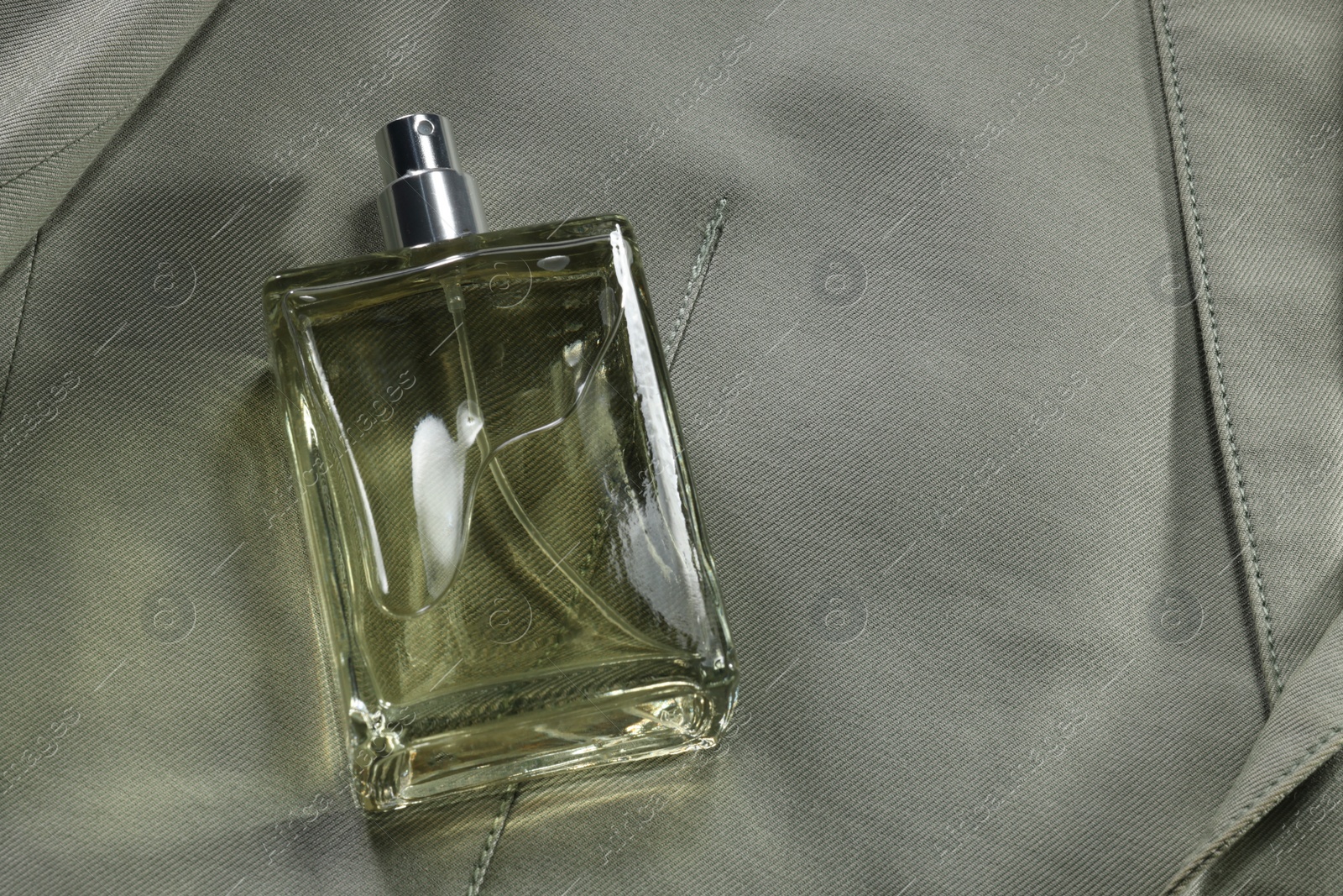 Photo of Luxury men's perfume in bottle on grey jacket, above view. Space for text