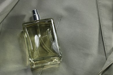 Luxury men's perfume in bottle on grey jacket, above view. Space for text