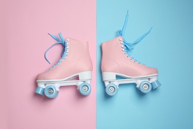 Pair of stylish quad roller skates on color background, top view