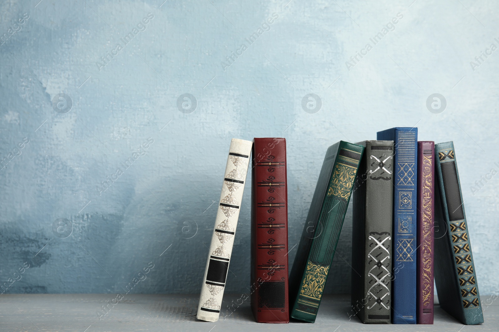 Photo of Collection of old books on grey wooden shelf. Space for text