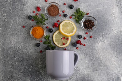 Cup and ingredients for immunity boosting tea on grey table, flat lay