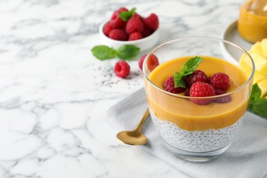 Delicious chia pudding with mango sauce and raspberries on white marble table. Space for text