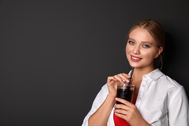 Photo of Young woman with glass of cola on black background, space for text. Refreshing drink