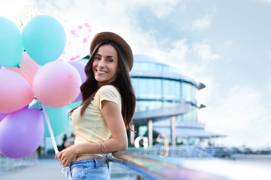 Photo of Beautiful young woman with color balloons on city street