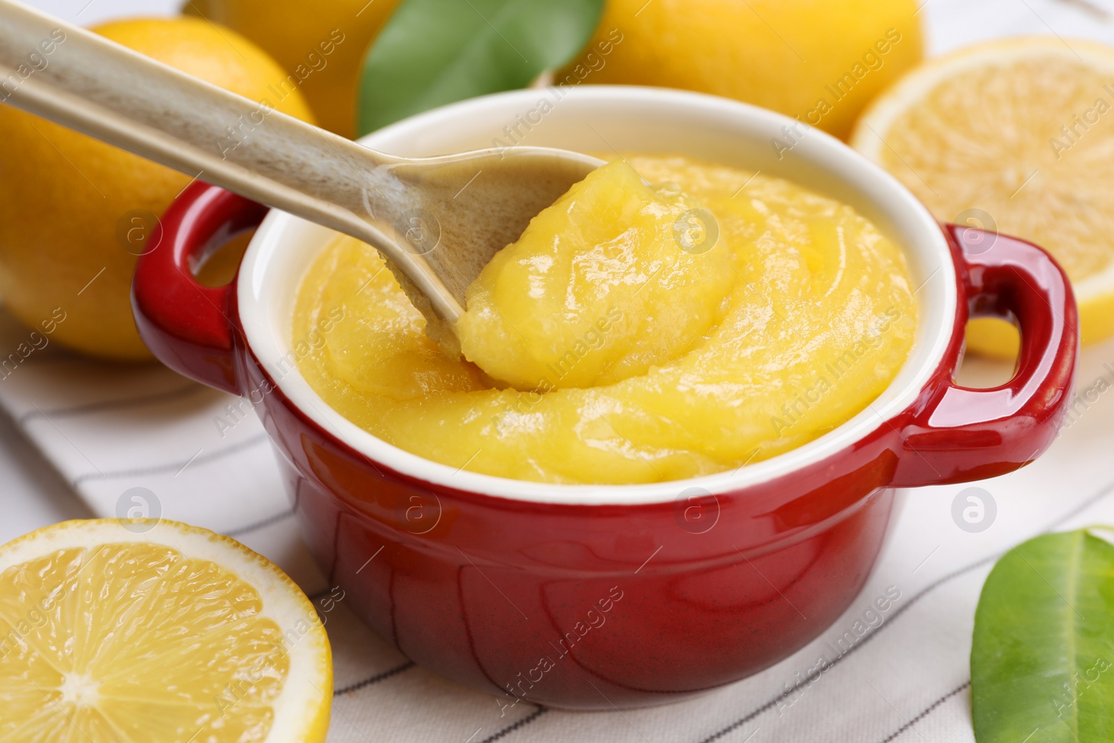 Photo of Taking delicious lemon curd from bowl at table, closeup