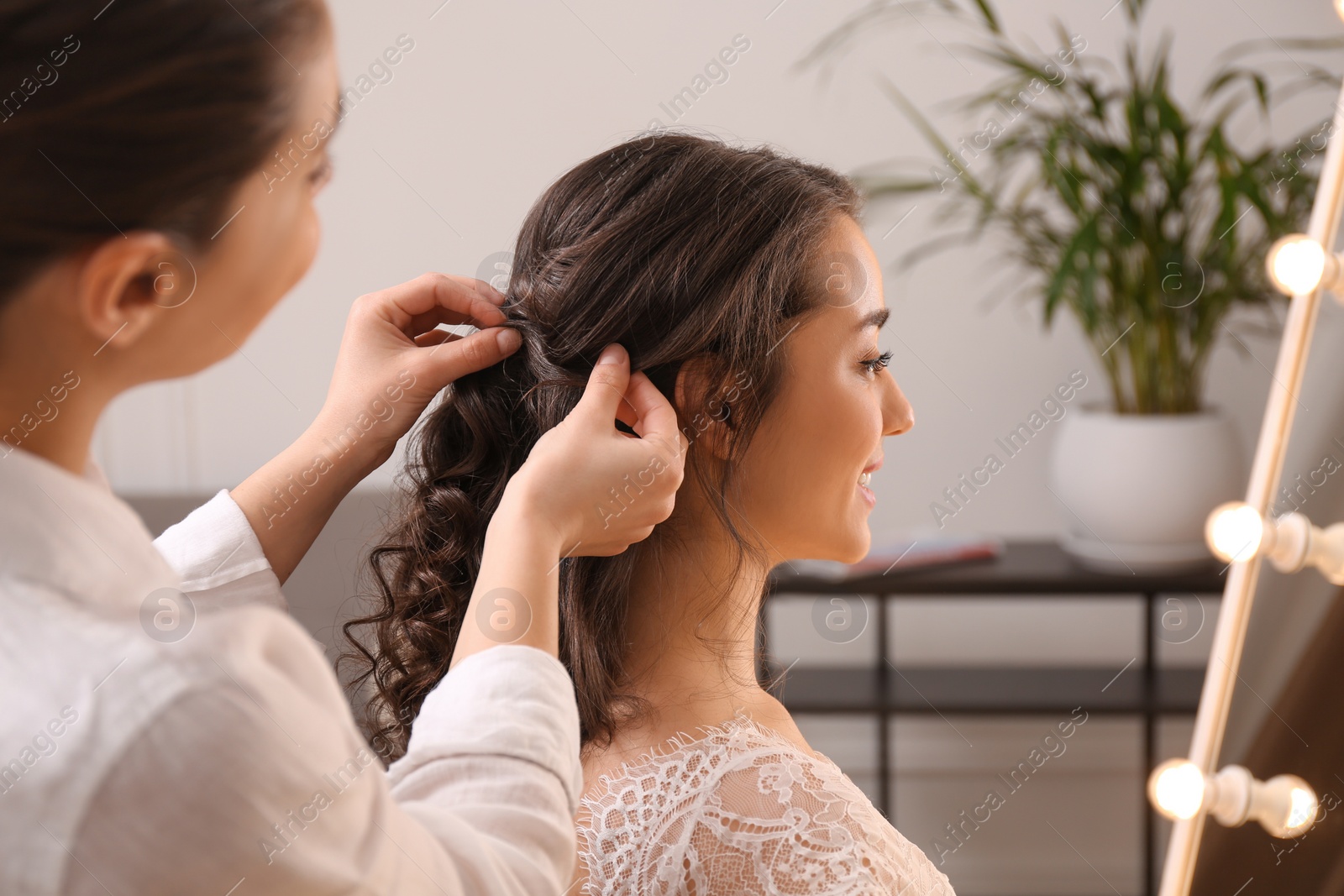 Photo of Stylist working with client in salon, making wedding hairstyle