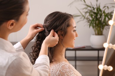 Stylist working with client in salon, making wedding hairstyle
