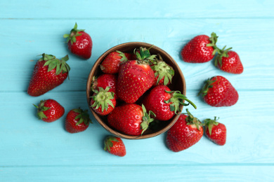 Photo of Delicious ripe strawberries in bowl on light blue wooden table, flat lay