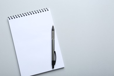 One notebook and pen on light grey background, top view. Space for text