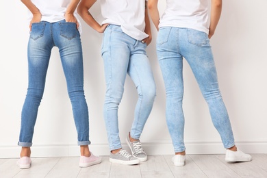 Photo of Group of young women in jeans near light wall