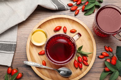Photo of Fresh rose hip tea, honey and berries on wooden table, flat lay