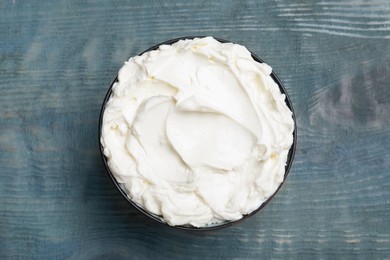 Photo of Tasty cream cheese on light blue wooden table, top view