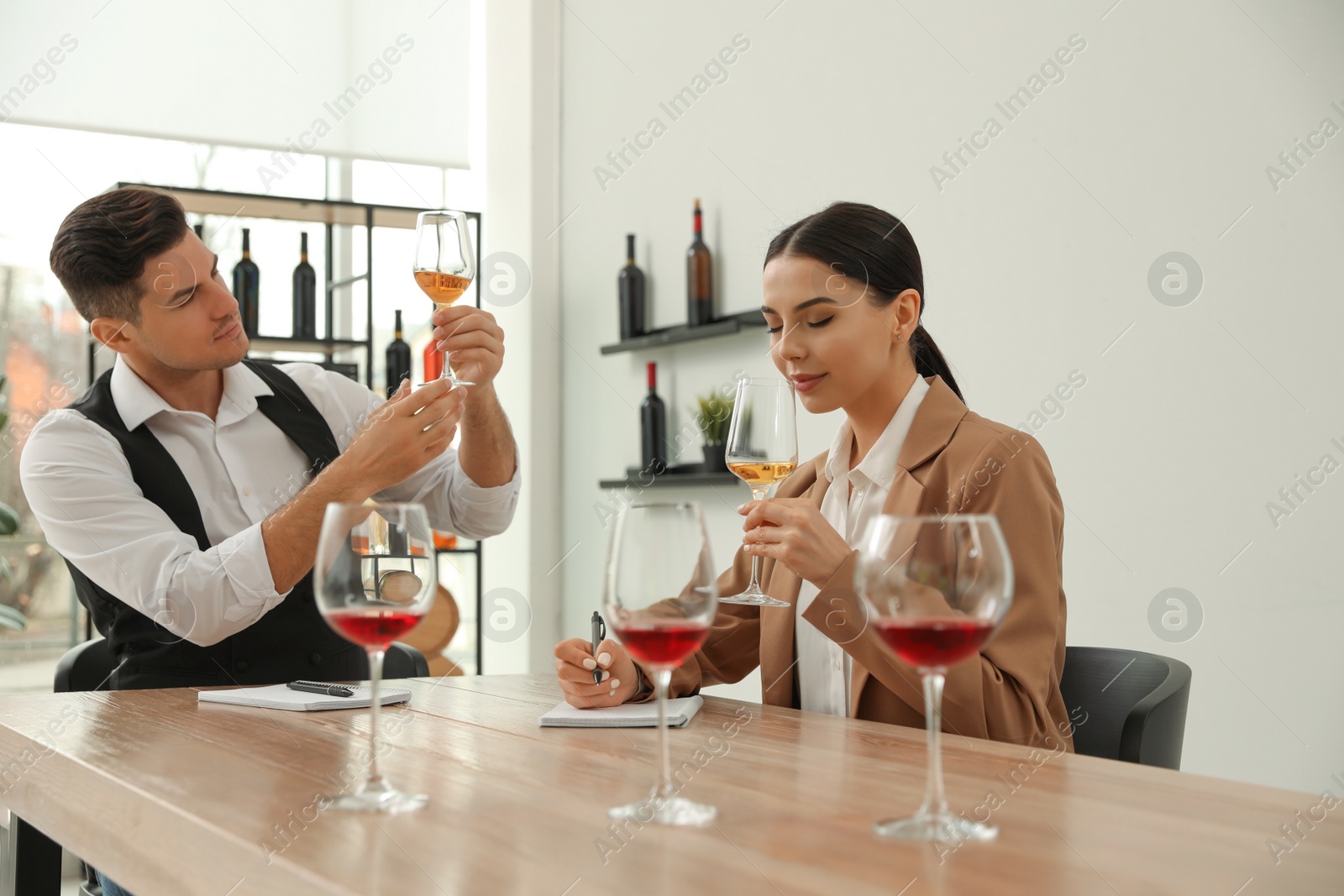 Photo of Sommeliers tasting different sorts of wine at table indoors