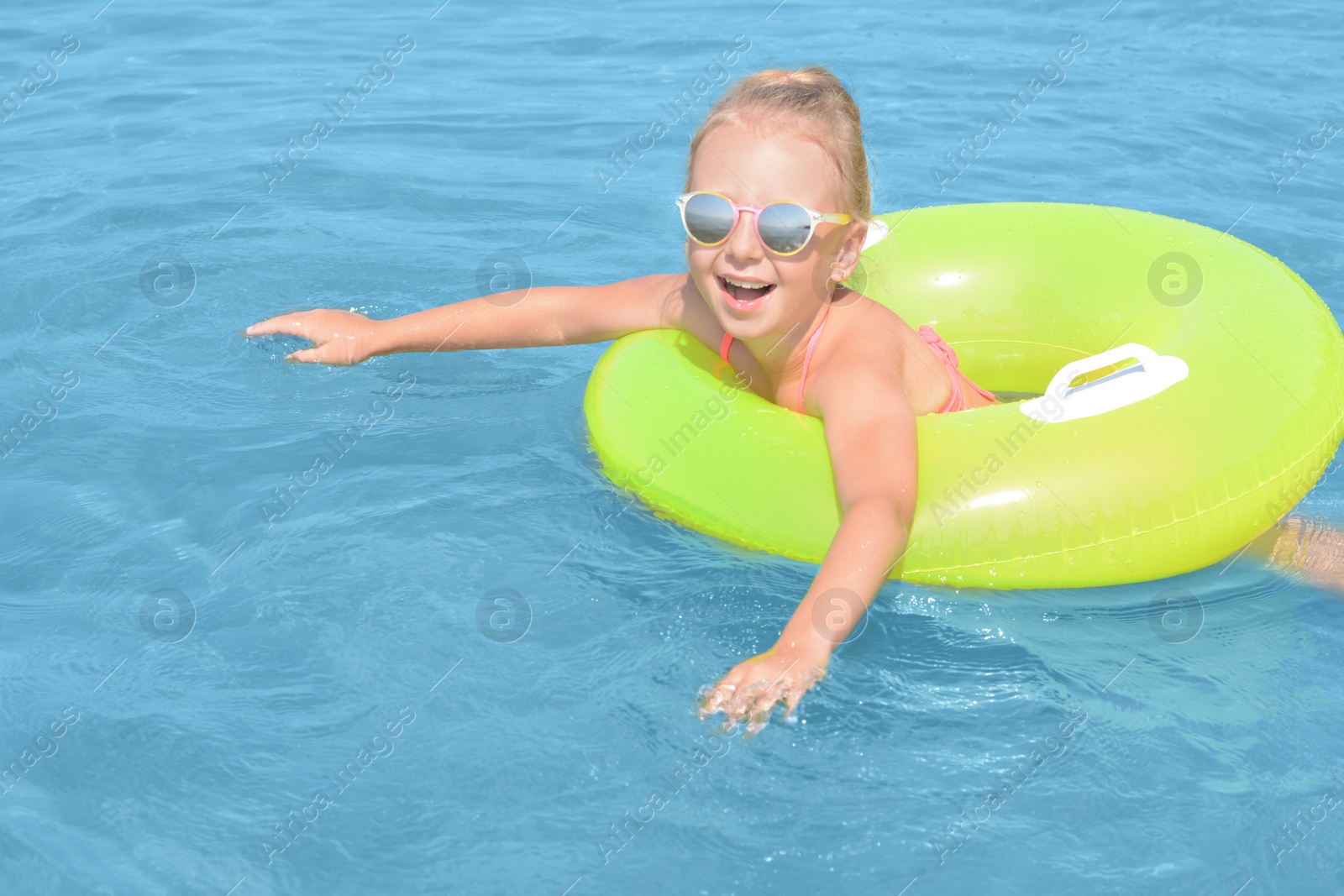 Photo of Happy little girl with inflatable ring in sea on sunny day