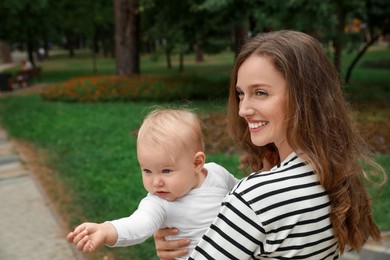 Photo of Mother with her cute baby spending time together outdoors. Space for text