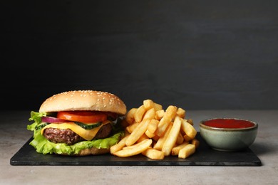 Photo of Delicious burger, ketchup and french fries served on grey table