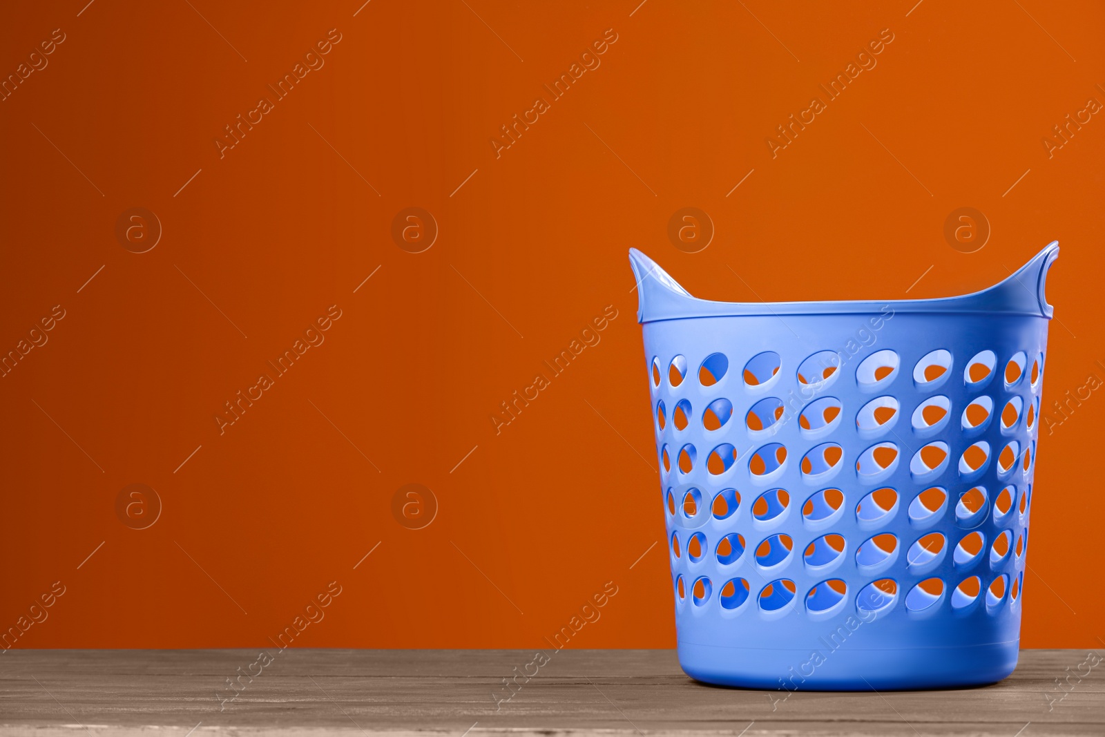 Photo of Empty plastic laundry basket near brown wall. Space for text