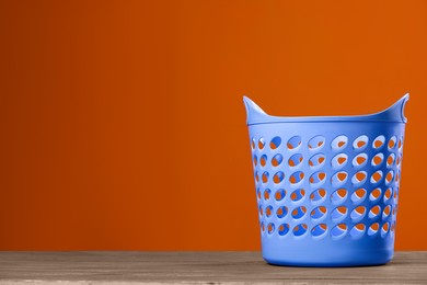 Photo of Empty plastic laundry basket near brown wall. Space for text