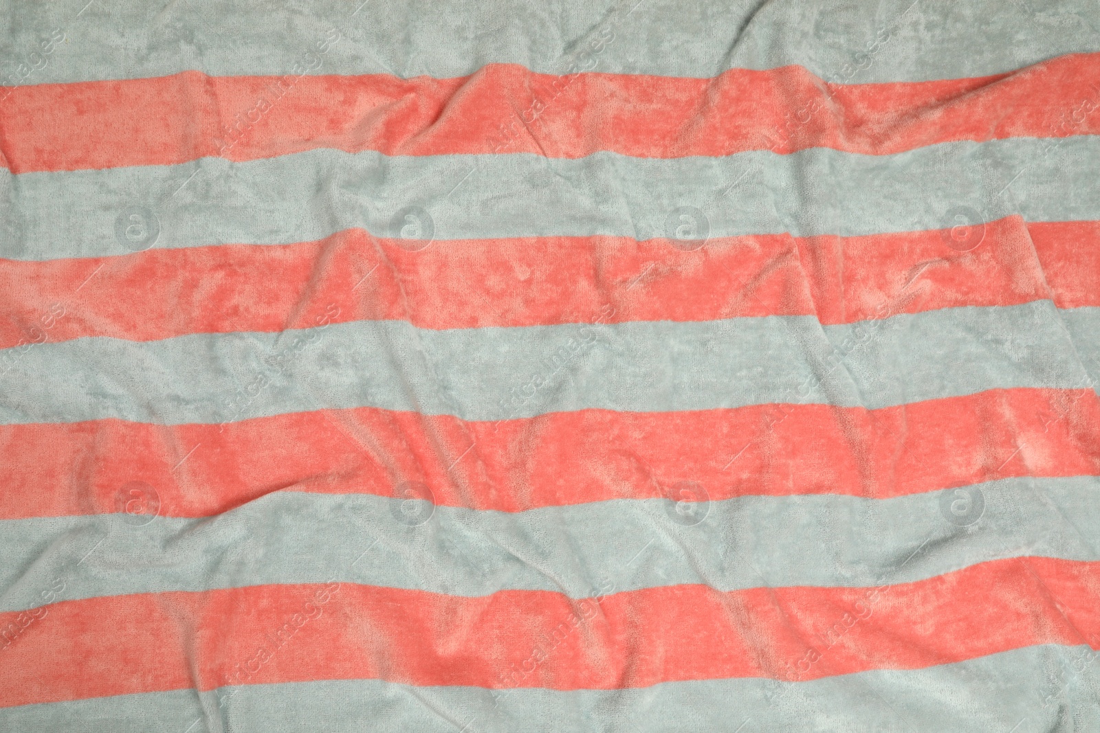 Photo of Crumpled striped beach towel as background, top view
