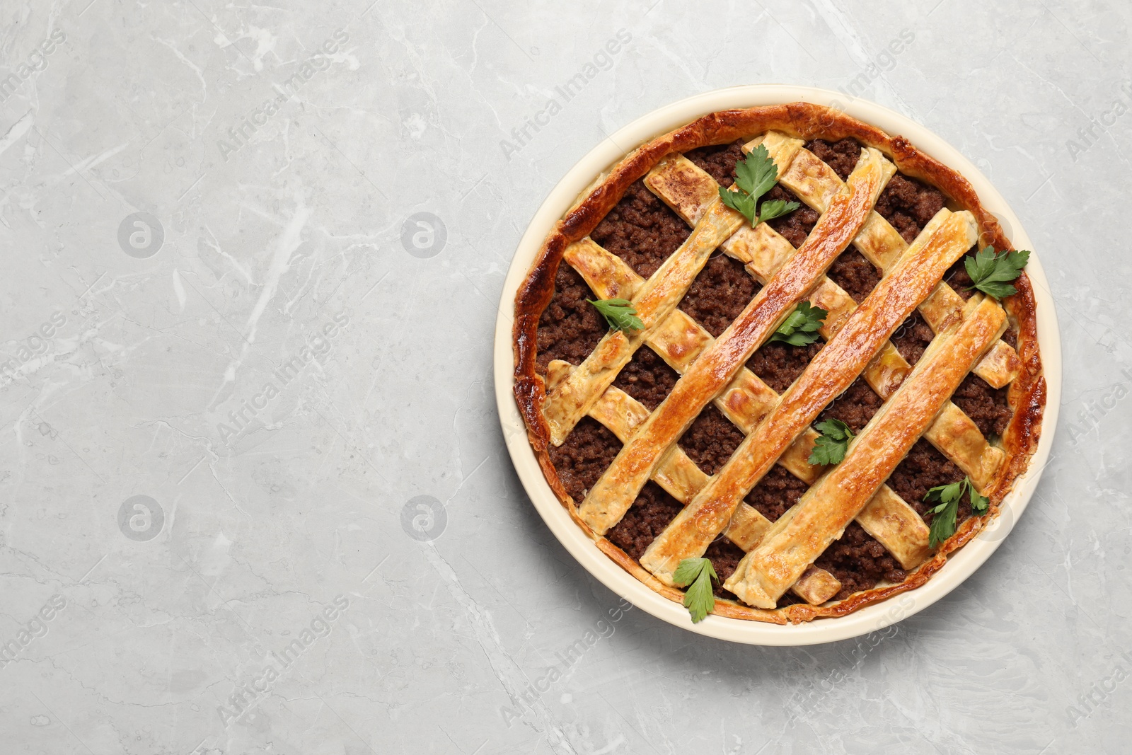 Photo of Freshly baked meat pie on light grey table, top view. Space for text