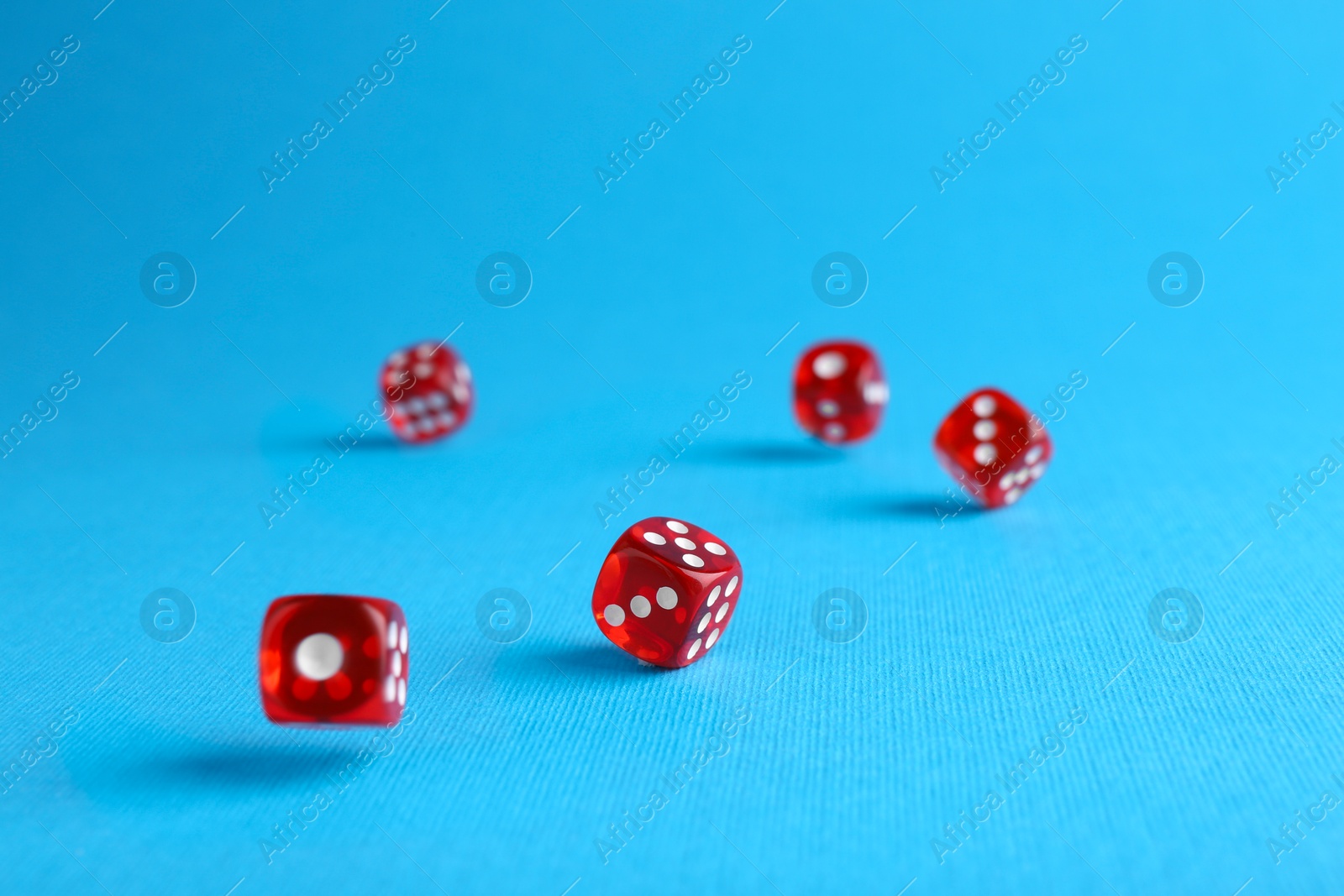 Photo of Many red game dices falling on light blue background