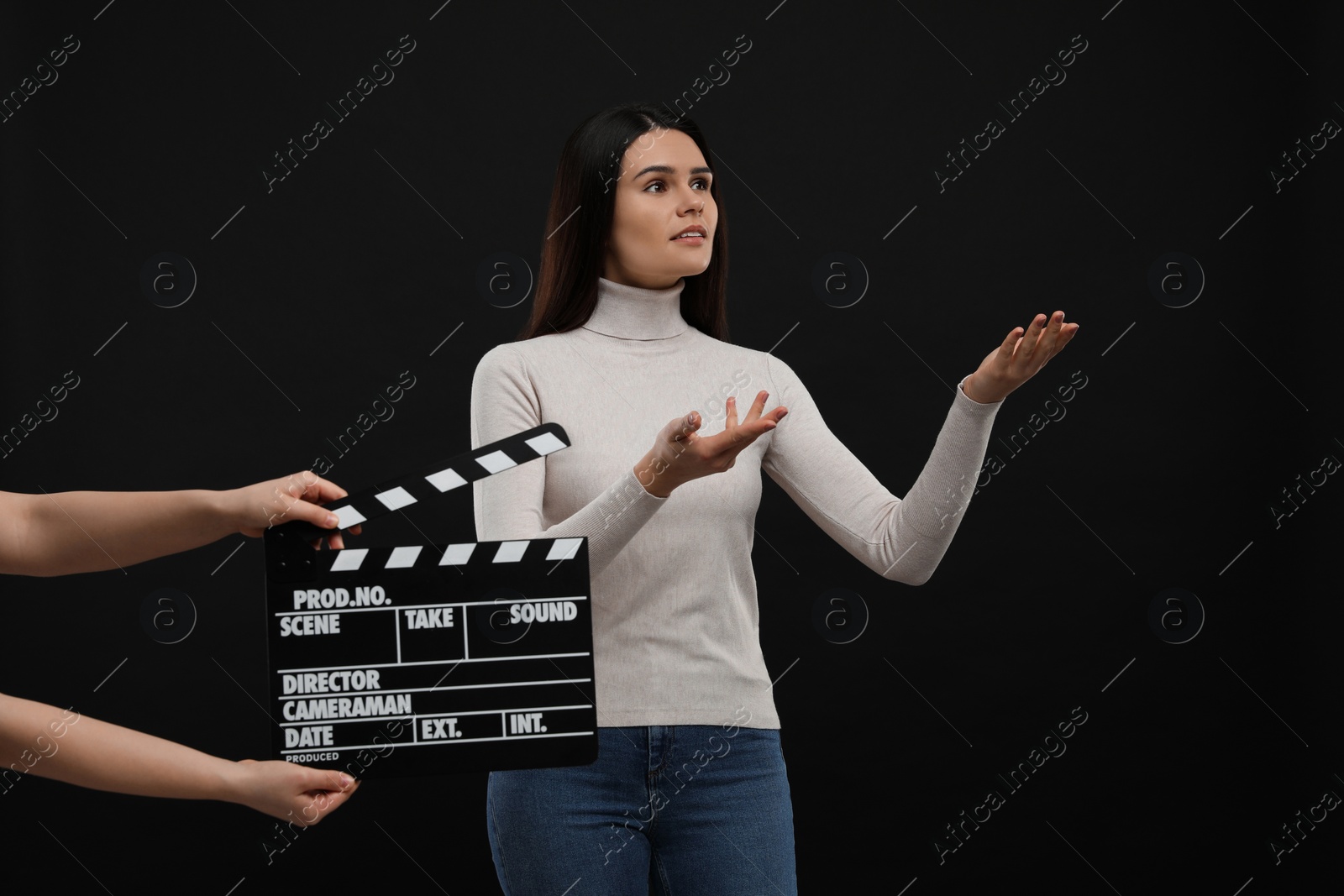 Photo of Actress performing while second assistant camera holding clapperboard on black background. Film industry