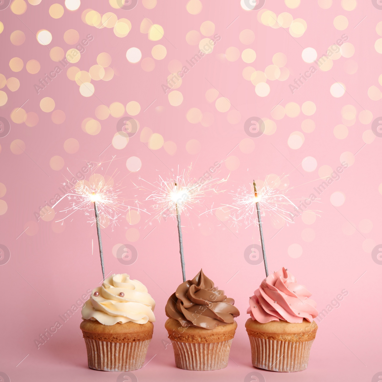 Image of Birthday cupcakes with sparklers on pink background