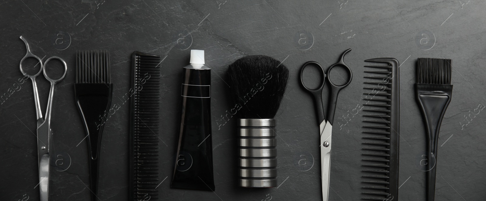 Image of Set of different professional tools for hair dyeing on black stone background, flat lay. Banner design