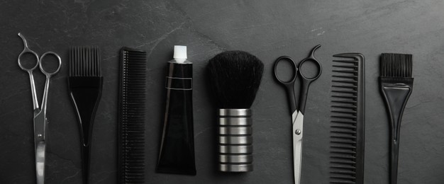 Set of different professional tools for hair dyeing on black stone background, flat lay. Banner design