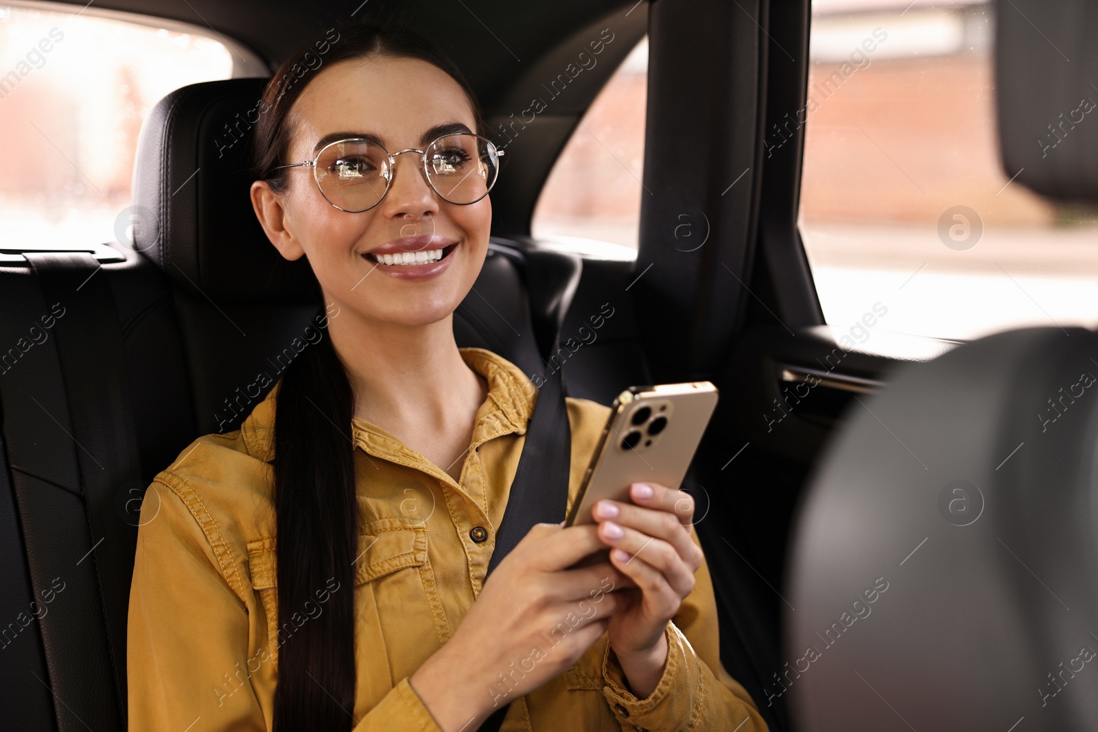 Photo of Woman with seatbelt using phone inside car