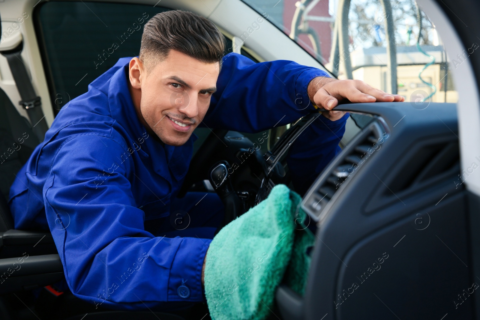 Photo of Car wash worker cleaning modern automobile interior