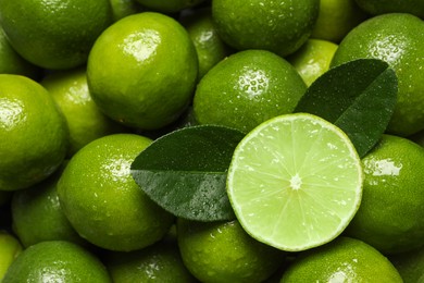 Photo of Fresh limes and leaves with water drops as background, top view